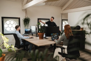 Eigenaar van Prikr vertelt twee collega's vanaf zijn bureau wat een webapplicatie is.