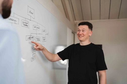 Een plan wordt opgesteld door Jasper die bij een whiteboard staat om een website te laten maken.