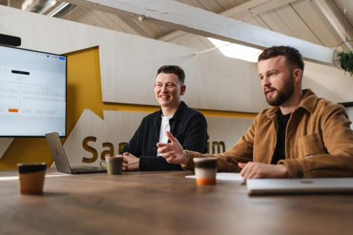 Twee software architecten van Prikr bespreken de architectuur voor software op maat, met een digitaal stroomschema op de achtergrond.
