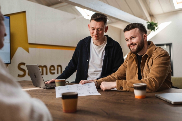 Collega's bespreken een app op de telefoon, urenregistratie app op maat voor het MKB