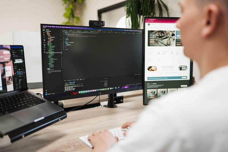 Ontwikkelaar bouwt aan code achter twee schermen, ontwikkeling van een voorraadsysteem op maat